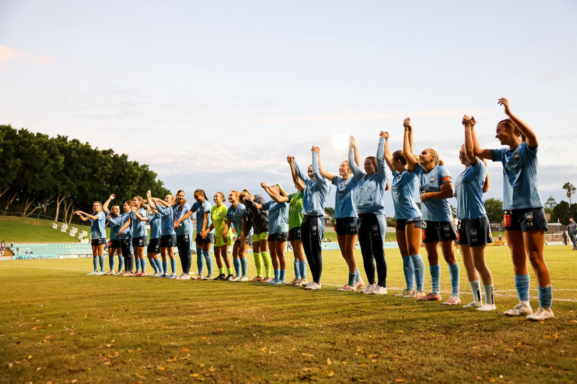 Sydney FC Women players holding hands and celebrating with fans after a match