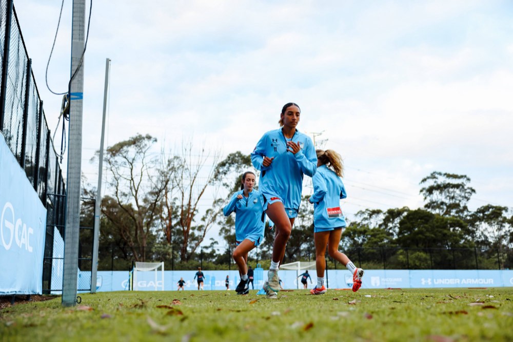 Sydney FC players jogging through a warm-up at training